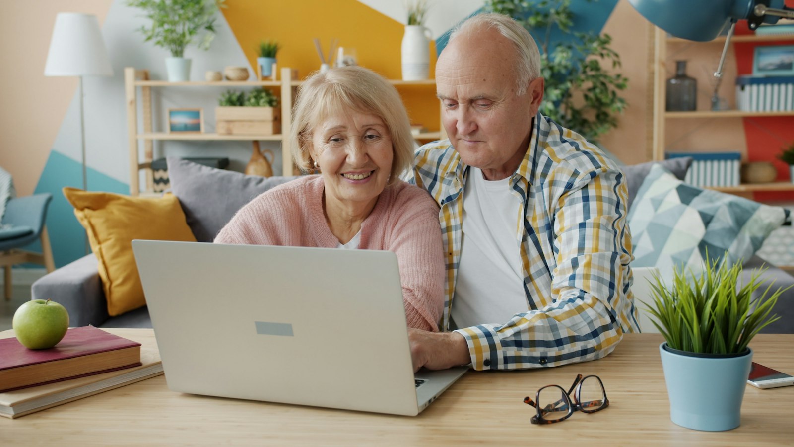An older couple smiling while looking at a laptop together